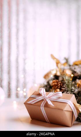 Boîte cadeau en carton Kraft attachée avec une corde de jute rugueuse sur fond de bois gris avec des branches d'arbre de Noël et des décorations de Noël Banque D'Images
