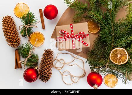 Boîte cadeau en carton Kraft attachée avec une corde de jute rugueuse sur fond de bois gris avec des branches d'arbre de Noël et des décorations de Noël Banque D'Images