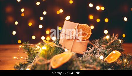 Boîte cadeau en carton Kraft attachée avec une corde de jute rugueuse sur fond de bois gris avec des branches d'arbre de Noël et des décorations de Noël Banque D'Images