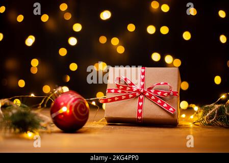 Boîte cadeau en carton Kraft attachée avec une corde de jute rugueuse sur fond de bois gris avec des branches d'arbre de Noël et des décorations de Noël Banque D'Images