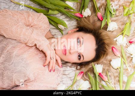 Portrait d'une jeune femme sur un lit avec des tulipes dans ses cheveux Banque D'Images