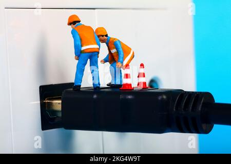 Des ouvriers miniatures inspectent une prise de télévision HDMI et une interface de fiche Banque D'Images