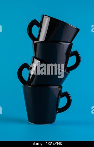 Une tour de tasses noires. Coupes noires minimalistes sur fond bleu Banque D'Images