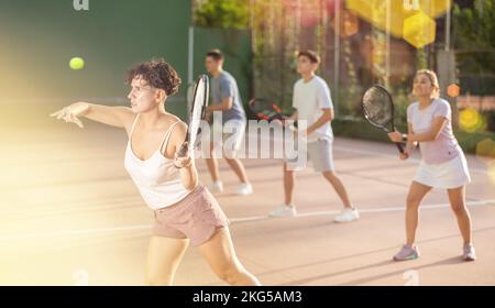 Femme servant le ballon pendant le jeu frontenis à l'extérieur Banque D'Images
