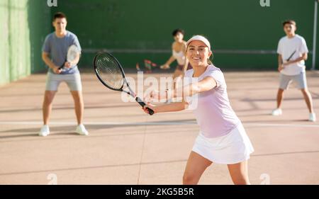 Femme servant le ballon pendant le jeu frontenis à l'extérieur Banque D'Images