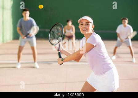 Expressive resolved fit girl jouant frontenis ball friendly match sur le terrain Banque D'Images