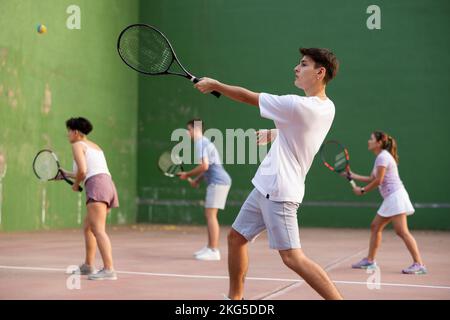 Jeune homme joueur de pelote frapper balle avec raquette Banque D'Images