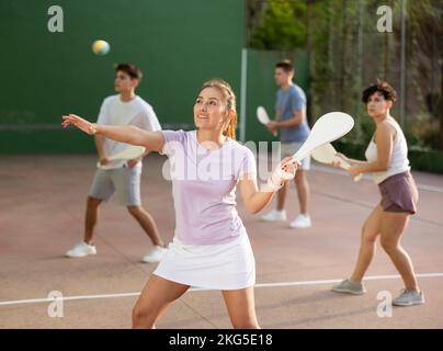 Femme servant le ballon pendant le jeu frontenis à l'extérieur Banque D'Images