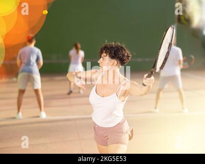 Femme sportive en short et t-shirt jouant frontenis sur le terrain Banque D'Images