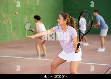 Femme servant le ballon pendant le jeu frontenis à l'extérieur Banque D'Images