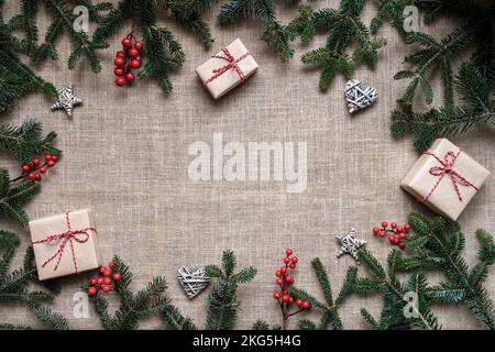 Cadre de Noël plat fait de branches d'épicéa, boîte-cadeau et ornements, sur fond de toile de fond. Concept de Noël . Vue de dessus avec espace de copie Banque D'Images
