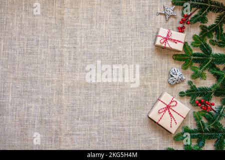 Cadre de Noël plat fait de branches d'épicéa, boîte-cadeau et ornements, sur fond de toile de fond. Concept de Noël . Vue de dessus avec espace de copie Banque D'Images