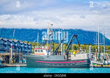 Remorqueur dans le port - Seward Alaska en été avec des arbres verts et de brouillard bas sur les montagnes derrière des condos rustiques en arrière-plan Banque D'Images