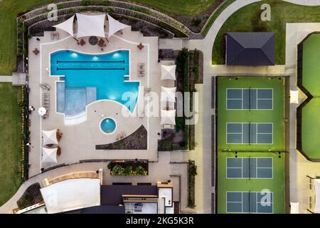 Vue aérienne sur les grands courts de tennis, piscine au centre de loisirs communautaire avec des demeures avec des salons en plein air en été. Banque D'Images