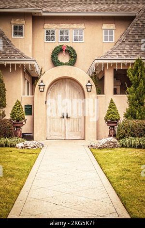 Trottoir menant à la porte voûtée de la maison moderne haut de gamme en stuc avec couronne de Noël et glaçons électriques Banque D'Images