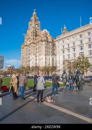 Scène de rue à Liverpool avec les touristes faisant la queue pour avoir des selfies avec les statues du célèbre groupe pop Beatles, ainsi que le bâtiment du foie Banque D'Images