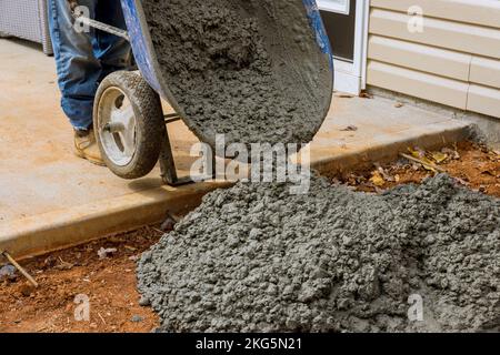 Avec l'aide de l'utilisation de brouettes, ils font de nouveaux chemins en béton près de la maison en versant du béton de ciment humide Banque D'Images