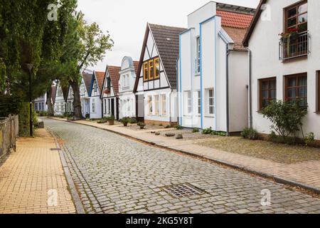 Rue résidentielle avec pavés rectangulaires, façades de maisons colorées avec toits en terre cuite, station balnéaire de Warnemunde, Rostock, Allemagne. Banque D'Images