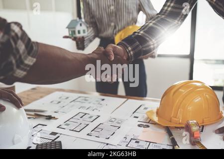 Architectes et ingénieurs ouvriers de construction qui se secouent la main après avoir fini un accord dans le chantier de construction de bureau, succès concept de collaboration Banque D'Images