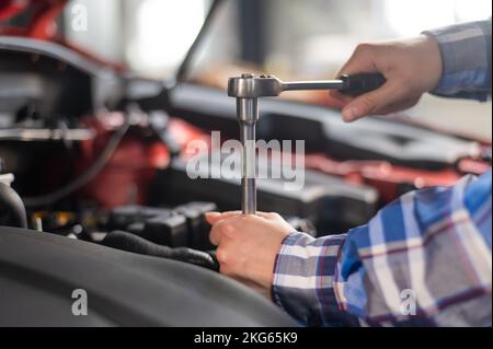 Mécanique automobile femelle en dévissant un écrou pour remplacer une bougie d'allumage de voiture. Banque D'Images