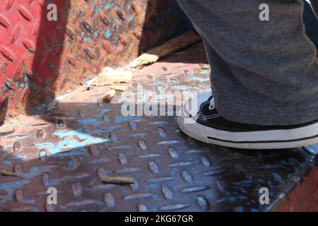 Un gros plan du pied d'un enfant portant un Converse All-Stars qui monte l'échelle jusqu'à un terrain de jeu en Amérique du Midwest. Banque D'Images