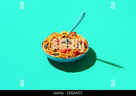 Plat italien, spaghetti à la sauce tomate, olives noires et câpres minimalistes sur une table verte. Assiette à pâtes vegan lumineuse sur fond vert Banque D'Images