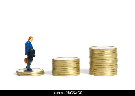 Photographie miniature de personnage de jouet de personnes. Un homme d'affaires monte dans les escaliers en pile de pièces. Isolé sur fond blanc. Photo d'image Banque D'Images