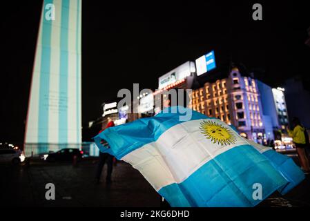 Buenos Aires, Argentine. 21st novembre 2022. Un garçon avec un drapeau argentin regarde l'Obélisque projeté avec des images faisant référence à la coupe du monde de football les supporters argentins réunis à côté de l'Obélisque la nuit avant que leur équipe ne participe à la coupe du monde de football. Crédit : SOPA Images Limited/Alamy Live News Banque D'Images