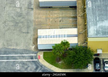 Vue de dessus du centre logistique géant avec de nombreux camions de remorques commerciales qui déchargent et chargent des produits de vente au détail pour une expédition ultérieure. Économie mondiale Banque D'Images