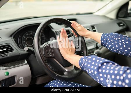 Une femme pilote fait roder l'avertisseur sonore de sa voiture pour éviter un accident. Concept de sécurité de conduite Banque D'Images