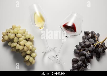 Les verres à vin avec des boissons blanches et rouges sont entre les raisins. Banque D'Images