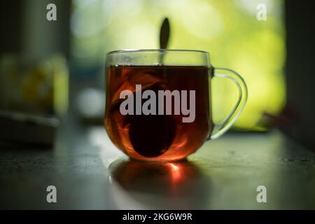 Thé sur table le matin. Verre de thé. Boisson pour le petit déjeuner. Sac de préparation dans de l'eau bouillante. Banque D'Images