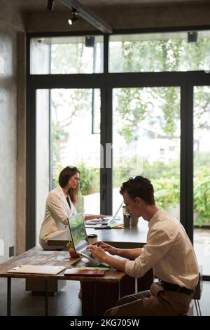Jeunes gens d'affaires travaillant sur des ordinateurs portables dans un café Banque D'Images