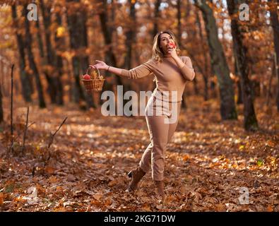 Plus taille bonne femme dans la forêt de chênes en automne, avec un panier de pommes pour pique-nique Banque D'Images