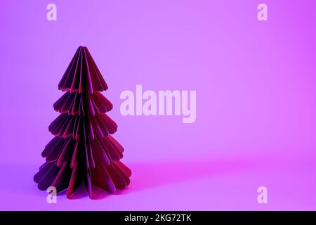 Sapin de Noël décoratif en papier sur fond rose avec une lumière néon tendance. Banque D'Images