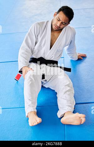 Sports, blessures et douleur dans les jambes sur le plancher de dojo de forme de karaté pour le tournoi, l'entraînement ou l'entraînement. Uniforme professionnel d'athlète d'homme des arts martiaux Banque D'Images