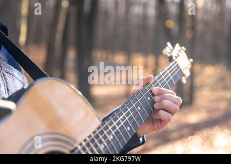 Gros plan, un homme joue une guitare acoustique dans la forêt d'automne. Banque D'Images
