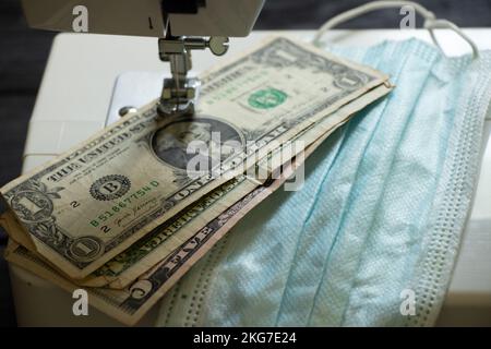 Les dollars américains se trouvent à côté des masques médicaux sur une machine à coudre, la production de masques médicaux, l'argent Banque D'Images