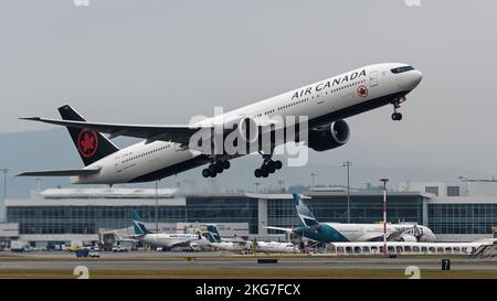 Richmond, Colombie-Britannique, Canada. 21st novembre 2022. Un Boeing 777-300ER (C-FIUR) d'Air Canada quitte l'aéroport international de Vancouver. En arrière-plan, les avions WestJet se sont garés au terminal intérieur de l'aéroport. (Image de crédit : © Bayne Stanley/ZUMA Press Wire) Banque D'Images