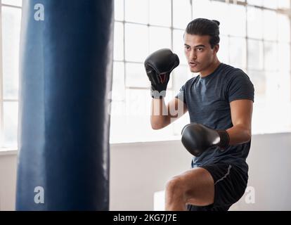 Fitness, boxe et entraînement d'homme pour une compétition de combat, d'entraînement ou de match avec un sac de boxe dans la salle de gym. Sport, motivation et athlète boxer faire Banque D'Images