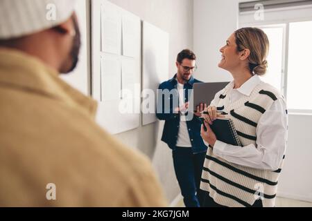 Les hommes d'affaires qui réussissent regardent certains rapports sur un tableau d'affichage dans un bureau créatif. Groupe de collègues heureux travaillant en équipe en un mois Banque D'Images