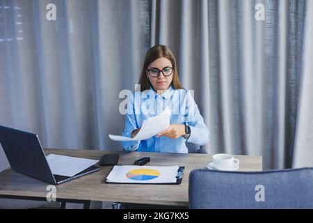 Une femme responsable est folle à son bureau et jette des documents. Une journée de travail dure au bureau. Travailleur émotionnel. Banque D'Images