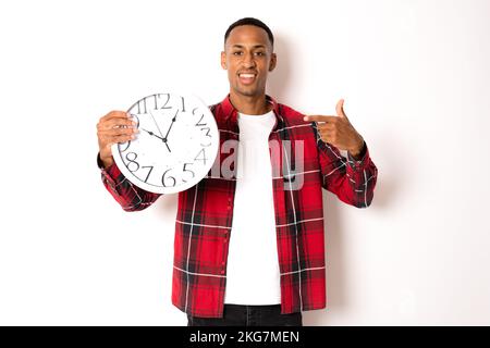 Jeune homme souriant tenant une grande horloge. Portrait sur fond blanc Banque D'Images