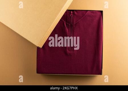 Gros plan du sweat-shirt rouge dans l'emballage et espace de copie sur fond jaune Banque D'Images