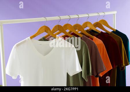 T-shirts de couleur sur le rail de vêtements et espace de copie sur fond violet Banque D'Images