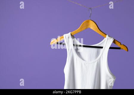 T-shirt suspendu sur un porte-manteau et espace pour copier sur fond violet Banque D'Images