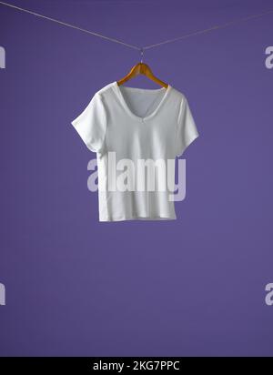 T-shirt suspendu sur un porte-manteau et espace pour copier sur fond violet Banque D'Images