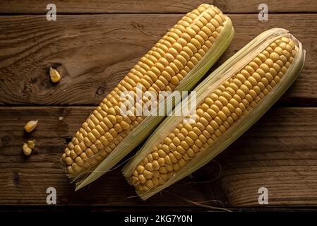 Deux épis de maïs (Zea mays) sur fond de bois rustique. vue de dessus Banque D'Images