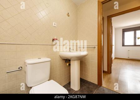 Petit vestiaire avec lavabo en porcelaine sur pied, murs carrelés carrés et boiseries en chêne Banque D'Images