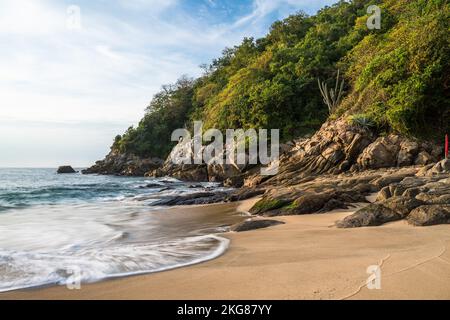 Vagues arrivant à terre sur la plage de Chahue dans les Bahias de Huatulco, au Mexique. Une vitesse d'obturation lente donne un aspect soyeux à l'eau. Banque D'Images